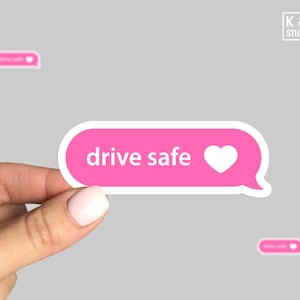 May include: Pink and white sticker with a text message bubble design. The text reads "drive safe" with a white heart icon.