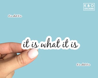 Può includere: Un adesivo in vinile fustellato con la frase it is what it is scritta in un carattere corsivo nero con un bordo bianco. L'adesivo è mostrato su uno sfondo azzurro con un logo K & O STICKERS nell'angolo in alto a destra.