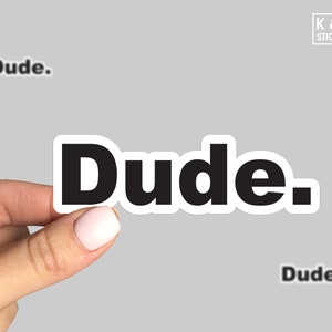 May include: Black and white sticker with the word "Dude." printed in bold, white outline.