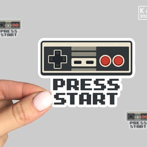 May include: A white ceramic mug with a black handle and the text "But First, Coffee" in a black, bold font. The mug is on a white surface.