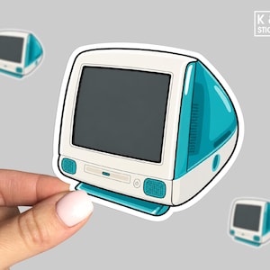 May include: A die-cut sticker featuring a retro-style desktop computer with a translucent teal casing, a white front bezel, and a dark gray screen. The design includes a CD drive slot, two small speakers, and a power button. The logo K & O STICKERS is visible.