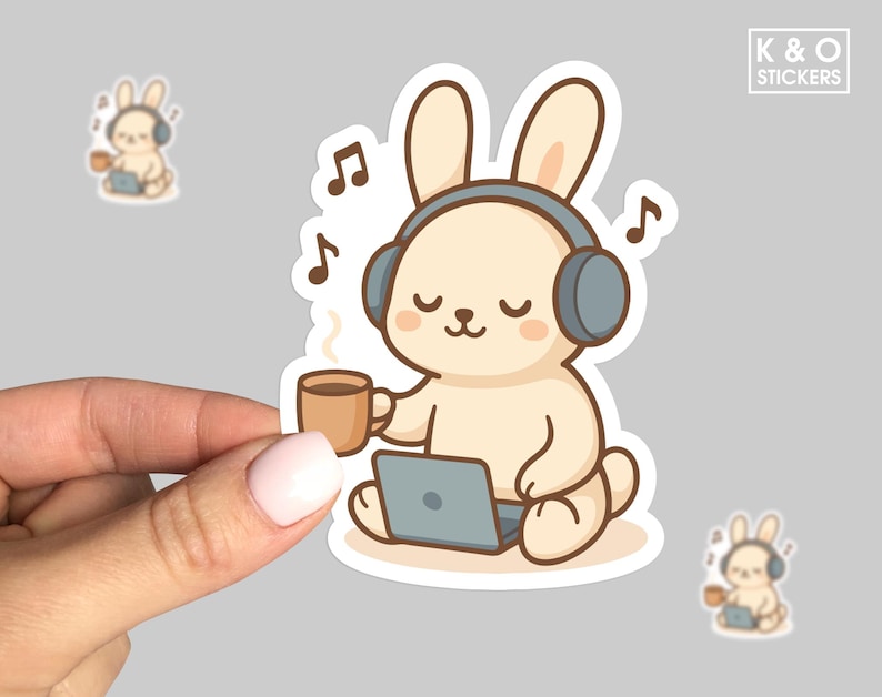 Adorable sticker featuring a relaxed bunny wearing oversized headphones, holding a warm coffee mug, and sitting with a laptop. Surrounded by floating music notes, the design gives off a calm, cozy aesthetic—perfect for lofi lovers and cute desk decor fans. White border and hand-holding shown for scale.
