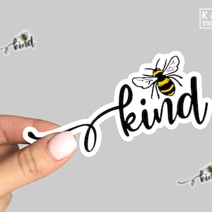 May include: A black and white sticker with a bee and the word "kind" in cursive. The bee is yellow and black and has wings.