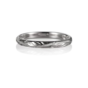May include: A simple silver wedding band with a delicate engraved design.