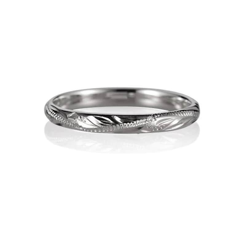 May include: A simple silver wedding band with a delicate engraved design.
