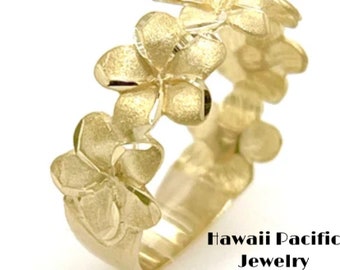May include: A gold ring with a design of multiple plumeria flowers. The ring is made of 14k gold and is a popular choice for Hawaiian wedding bands.