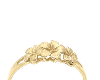 Puede incluir: Un anillo de oro con tres diseños de flores. Las flores están dispuestas en una fila y están conectadas por una banda delgada.