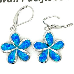 May include: A pair of silver earrings with blue opal flower charms. The flowers have five petals and are set in a silver frame.
