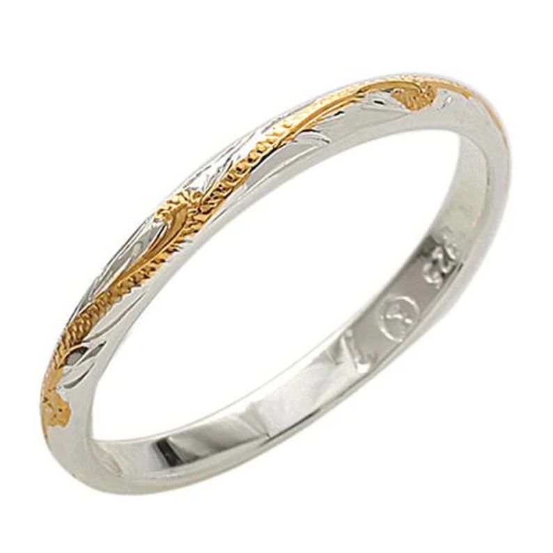 May include: A thin silver band with a gold engraved design. The band is simple and elegant.