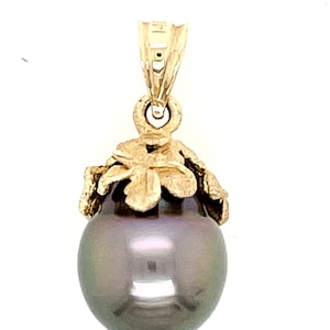 Puede incluir: Colgante de oro con una gran perla gris oscura. La perla est&aacute; rematada con un dise&ntilde;o floral dorado y sujeta a una reasa dorada. El colgante est&aacute; dise&ntilde;ado para ser usado como collar.