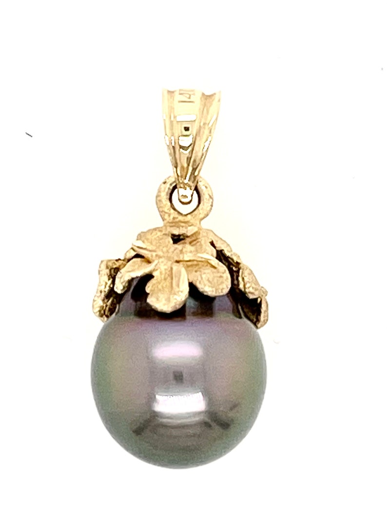 Puede incluir: Colgante de oro con una gran perla gris oscura. La perla est&aacute; rematada con un dise&ntilde;o floral dorado y sujeta a una reasa dorada. El colgante est&aacute; dise&ntilde;ado para ser usado como collar.