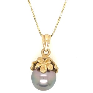 Puede incluir: Collar dorado con un colgante de perla gris. El colgante presenta un engaste en forma de flor. La cadena es una fina cadena de caja. El texto "Hawaii Pacific Jew" es visible en la parte superior.