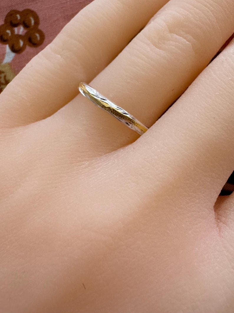 May include: A thin silver band with a delicate etched design.