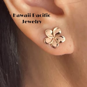 May include: A pair of gold-tone flower-shaped earrings. The earrings are in the shape of a plumeria flower, a popular Hawaiian flower. The earrings are small and delicate, and they would make a great gift for someone who loves Hawaii.
