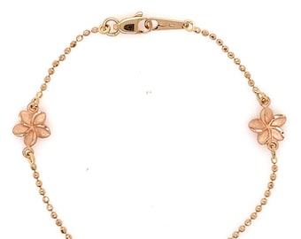 May include: A gold chain bracelet with three flower charms. The flowers are a light gold color and have a textured surface.