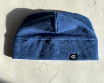 May include: A blue fleece beanie with a black label that says "Dome Fleece" on it.