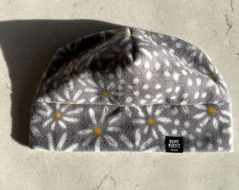 May include: Gray fleece beanie with a white daisy pattern and a black label that reads "Dome Fleece" in white text.