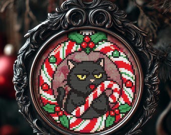 Könnte beinhalten: Weihnachtsbaumschmuck mit einer schwarzen Katze mit Zuckerstange, umgeben von einem rot-weiß gestreiften Rand und grünem Stechpalmenlaub. Der Schmuck befindet sich in einem dekorativen Silberrahmen.