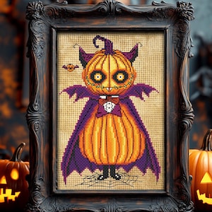 Puede incluir: Un patrón de punto de cruz de una calabaza vestida de vampiro con una capa morada y una pajarita. La calabaza tiene una boca y ojos cosidos. El fondo es una tela beige con una telaraña.