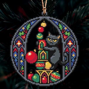 Op de afbeelding: Een kruissteek kerstversiering met een zwarte kat met gele ogen, omringd door kleurrijke ballen. De versiering heeft een glas-in-lood stijl rand met rode, blauwe en groene accenten. Een gouden draad is bevestigd om op te hangen.