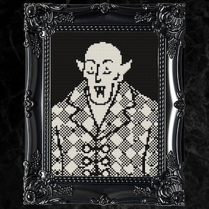 May include: Black and white pixel art cross stitch of a vampire with fangs, wearing a patterned jacket. The vampire has a bald head and pointy ears.