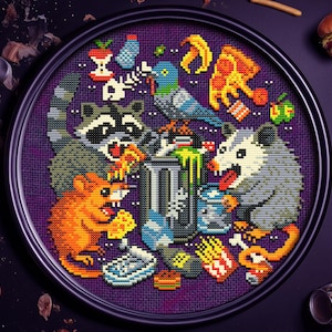 Puede incluir: Una obra de arte de punto de cruz que representa un cubo de basura rodeado de animales de dibujos animados, incluyendo un mapache, una rata y una zarigüeya, festejando con alimentos desechados como pizza, papas fritas y una hamburguesa. La obra está enmarcada en un marco circular negro.