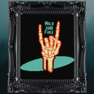 May include: A black and white pixel art design of a skeleton hand making the rock and roll hand gesture. The hand is orange and the background is black with a teal blue oval shape behind the hand. The text "WILD AND FREE" is above the hand in white.