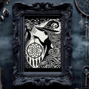 May include: Black and white framed artwork featuring a witch silhouette holding a dreamcatcher. The artwork is in a black ornate frame. The background is a dark, textured surface with decorative keys and feathers.