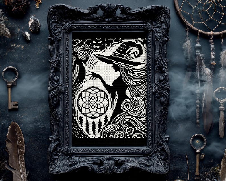 May include: Black and white framed artwork featuring a witch silhouette holding a dreamcatcher. The artwork is in a black ornate frame. The background is a dark, textured surface with decorative keys and feathers.