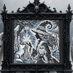 May include: A black and white cross-stitch embroidery framed in a black ornate frame. The design features a witch with a pointed hat, a fox, and an owl in a snowy forest setting.
