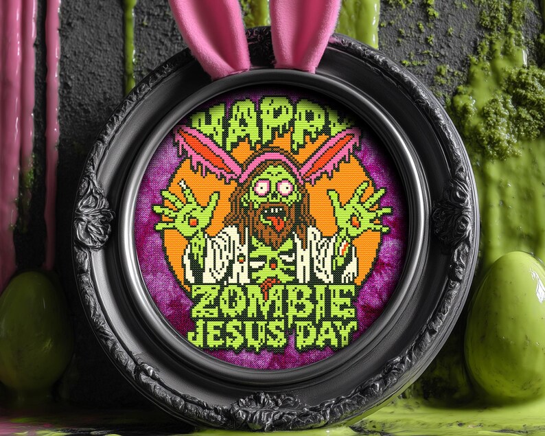 May include: A black framed embroidery hoop with a purple background and a green zombie Jesus wearing a bunny ear headband. The text reads "Happy Zombie Jesus Day".