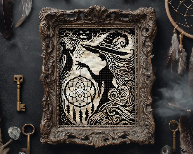 May include: Framed black and white cross-stitch art featuring a witch silhouette holding a dreamcatcher. The artwork is in an ornate brown frame. The witch has long flowing hair and a pointed hat. The dreamcatcher has a detailed web design.