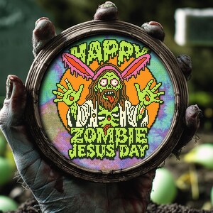 May include: A green zombie Jesus with bunny ears holding a sign that says "Happy Zombie Jesus Day" in a cross-stitch style embroidery hoop.