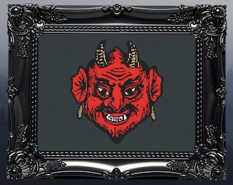 May include: A red devil face with horns, a pointed beard, and a mischievous grin. The face is framed in a black ornate frame.