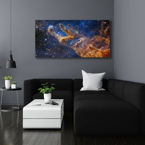 K&ouml;nnte beinhalten: Ein schwarzes Ecksofa mit einem wei&szlig;en Kissen vor einer Wand mit einem gro&szlig;en Druck einer Nebel in Blaut&ouml;nen, Orange und Gelb.