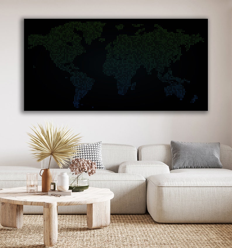 May include: A black and white world map with green and blue dots, hanging on a white wall above a white sofa with a brown and white patterned cushion and a grey cushion. A wooden coffee table with a vase of flowers, a book, and a glass candle holder sits in front of the sofa.
