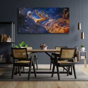 K&ouml;nnte beinhalten: Ein Esszimmer mit einer dunkelblauen Wand und einem gro&szlig;en Leinwanddruck einer Nebel in Blaut&ouml;nen, Orange und Gelb. Der Druck h&auml;ngt &uuml;ber einem Holztisch mit vier schwarzen St&uuml;hlen. Die St&uuml;hle haben geflochtene Korbsitze und -lehnen. Es gibt einen kleinen Holz-Beistelltisch mit einer Topfpflanze darauf.