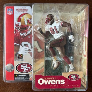 May include: A Terrell Owens San Francisco 49ers action figure in a clear plastic blister pack. The figure wears a white jersey with the number 81, brown trousers, and a helmet. The packaging features NFL branding, the 49ers logo, and player name text.