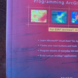 Peut inclure: Couverture du livre "Programming ArcGis" avec un fond rouge et un titre en texte blanc. La couverture pr&eacute;sente trois images de cartes avec diff&eacute;rentes gammes de couleurs. Le livre est destin&eacute; &agrave; ESRI ArcView et ArcGIS. La couverture du livre pr&eacute;sente &eacute;galement quatre puces d&eacute;crivant le contenu du livre&nbsp;: Apprendre Microsoft Visual Basic for Applications, Cr&eacute;er vos propres boutons et outils, Programmer des dizaines de t&acirc;ches SIG quotidiennes et Cr&eacute;er des applications ArcMap personnalis&eacute;es. Le nom de l'auteur, Robert Burke, est imprim&eacute; en bas de la couverture.