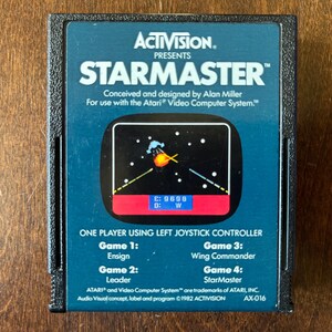 May include: A blue Atari game cartridge for StarMaster, a game conceived and designed by Alan Miller. The cartridge features a screenshot of the game with a spaceship and a starfield. The text "ACTIVISION. PRESENTS STARMASTER™" is printed on the front of the cartridge.