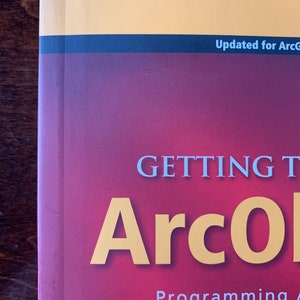 Peut inclure: Un livre rouge avec le titre "GETTING STARTED WITH ArcGIS Programming" en texte blanc et "ArcGIS" en texte jaune. Le livre a une bande noire et jaune en haut avec le texte "Updated for ArcGIS 10.1" en texte blanc.