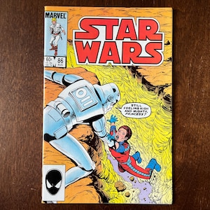 Puede incluir: Un cómic vintage de Star Wars, número 86, con una llamativa ilustración de portada. La imagen muestra un robot plateado y un personaje en rojo y azul. El título "STAR WARS" está en letras rojas grandes, con el logo de Marvel.