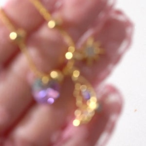 May include: A gold chain necklace with a star, crescent moon, and purple gemstone pendant.