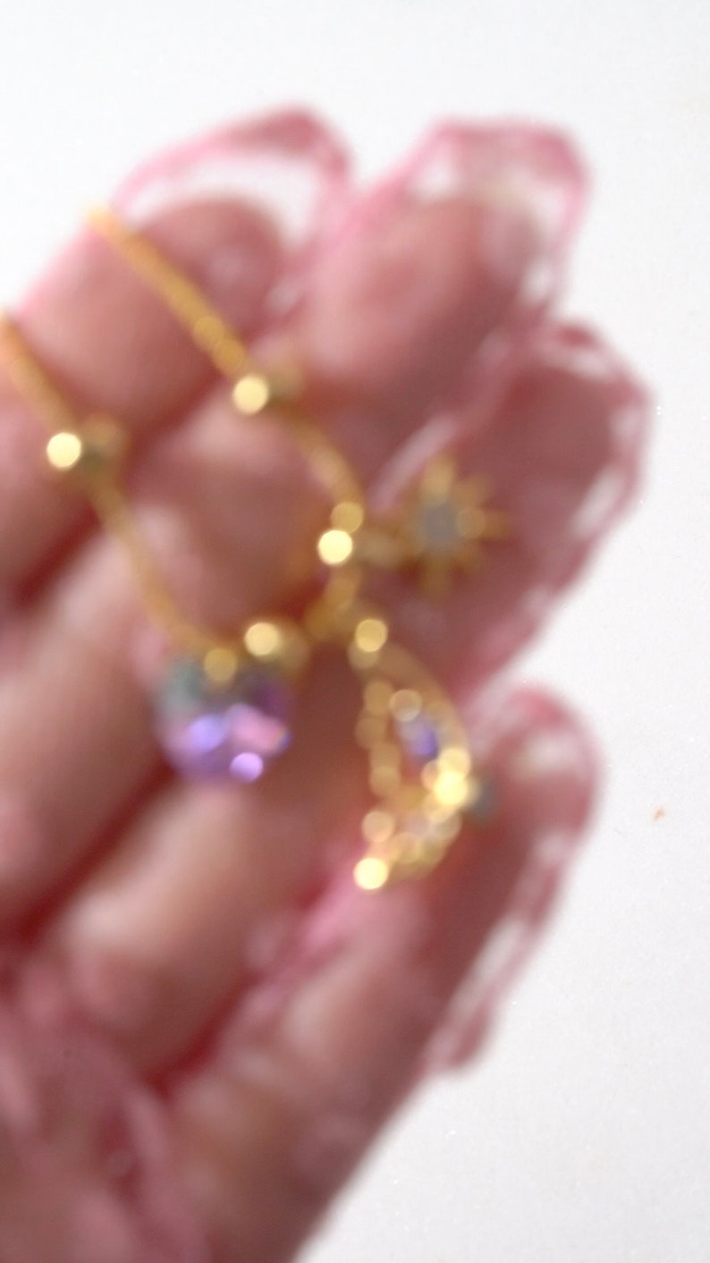 May include: A gold chain necklace with a star, crescent moon, and purple gemstone pendant.