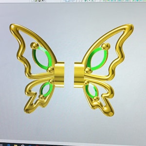 May include: A gold butterfly design with green accents. The butterfly is split into two pieces, with each piece having a wing.