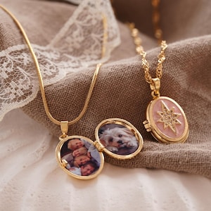 May include: Gold necklaces with oval lockets. One locket is open, showing a photo of children, and another displays a dog. A third locket features a pink starburst design. The necklaces are on a textured, neutral-toned surface.
