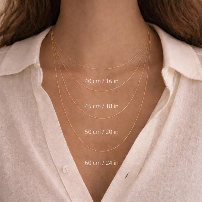 May include: Four delicate gold necklaces of varying lengths, displayed against a white shirt. The lengths are labeled: 16 in (40 cm), 18 in (45 cm), 20 in (50 cm), and 24 in (60 cm).