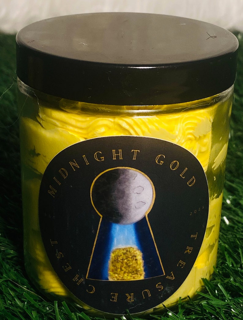 Op de afbeelding: Een gele pot met een zwart deksel en een zwart en gouden etiket met de tekst "Midnight Gold Treasure Chest". Het etiket heeft een sleutelgat met een maan en een goudklompje erin.