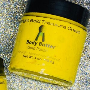 Op de afbeelding: Een gele pot met body butter met het label "Night Gold Treasure Chest Body Butter Gold Polish" en een sleutelgatlogo. De pot is 4 ounce of 113,4 gram.