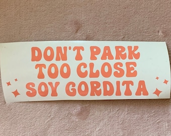 May include: White sticker with pink text that reads "Don't Park Too Close Soy Gordita" with two small pink stars on either side of the text.